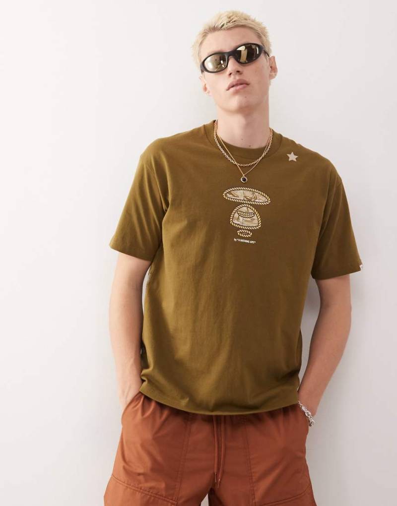 Aape by A Bathing Ape - Kastiges T-Shirt in Khakigrün mit mehreren platzierten Western-Prints von AAPE BY A BATHING APE®