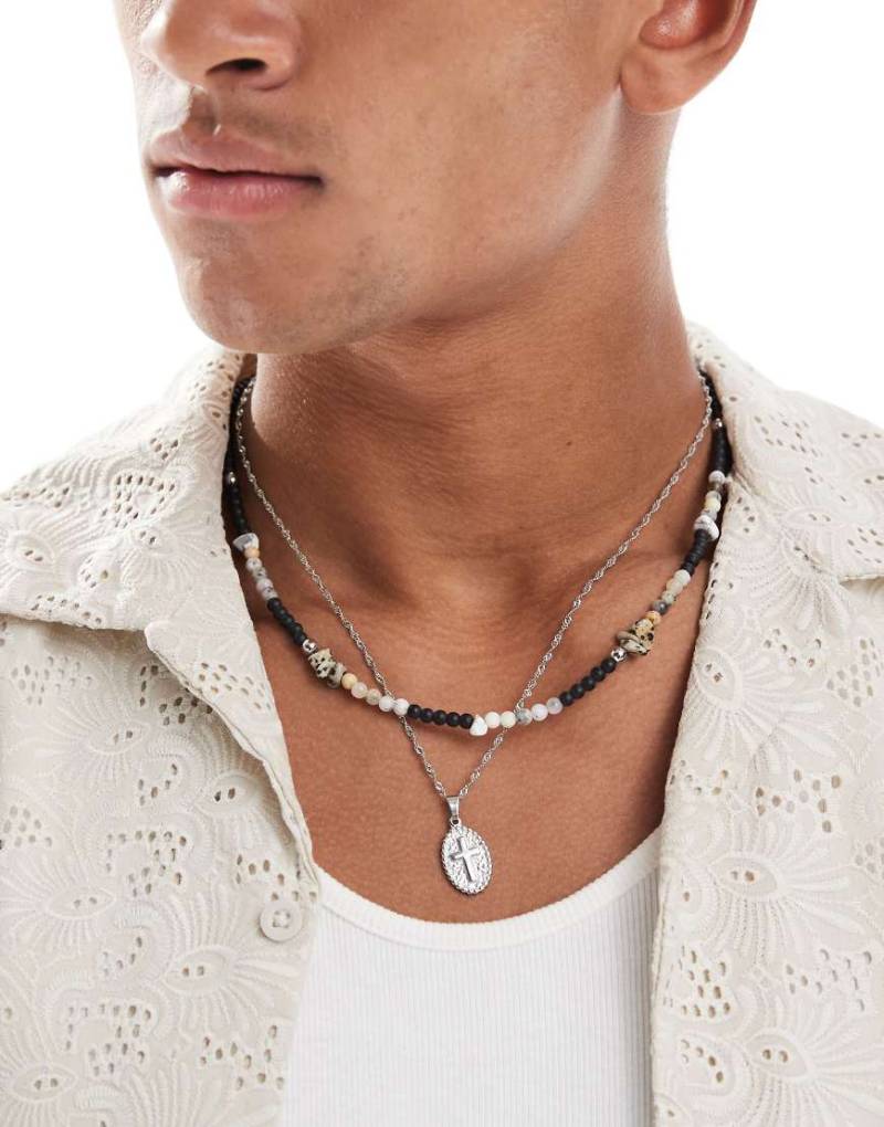 ASOS DESIGN - 2er-Pack Festival-Halskette in Silber und Schwarz mit Halbedelsteinperlen und Münzanhänger mit Kreuz von ASOS DESIGN