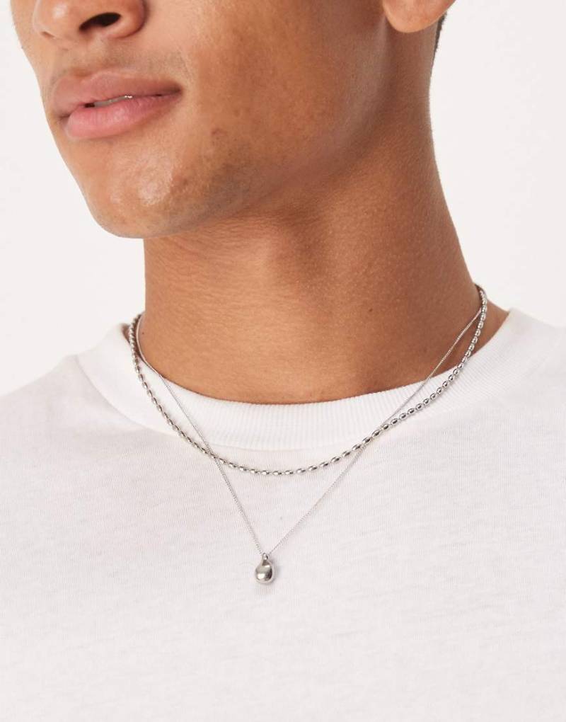 ASOS DESIGN - 2er-Pack silberfarbene Halsketten aus Edelstahl mit Anhänger in geschmolzener Optik von ASOS DESIGN