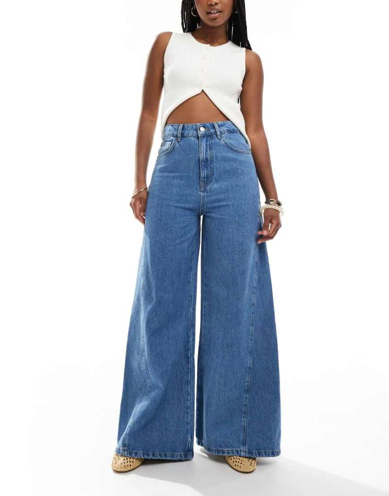 ASOS DESIGN - Ausgestellte Jeans in mittelblauer Waschung mit Godet-Einsätzen von ASOS DESIGN