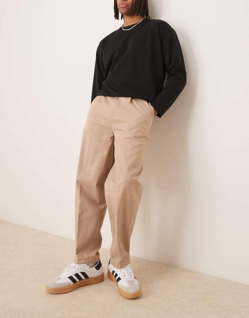 ASOS DESIGN - Elegante, schmal zulaufende Baumwoll-Chinohose in hellem Steinbeige mit Oversize-Schnitt und seitlichen Reglerlaschen-Neutral von ASOS DESIGN