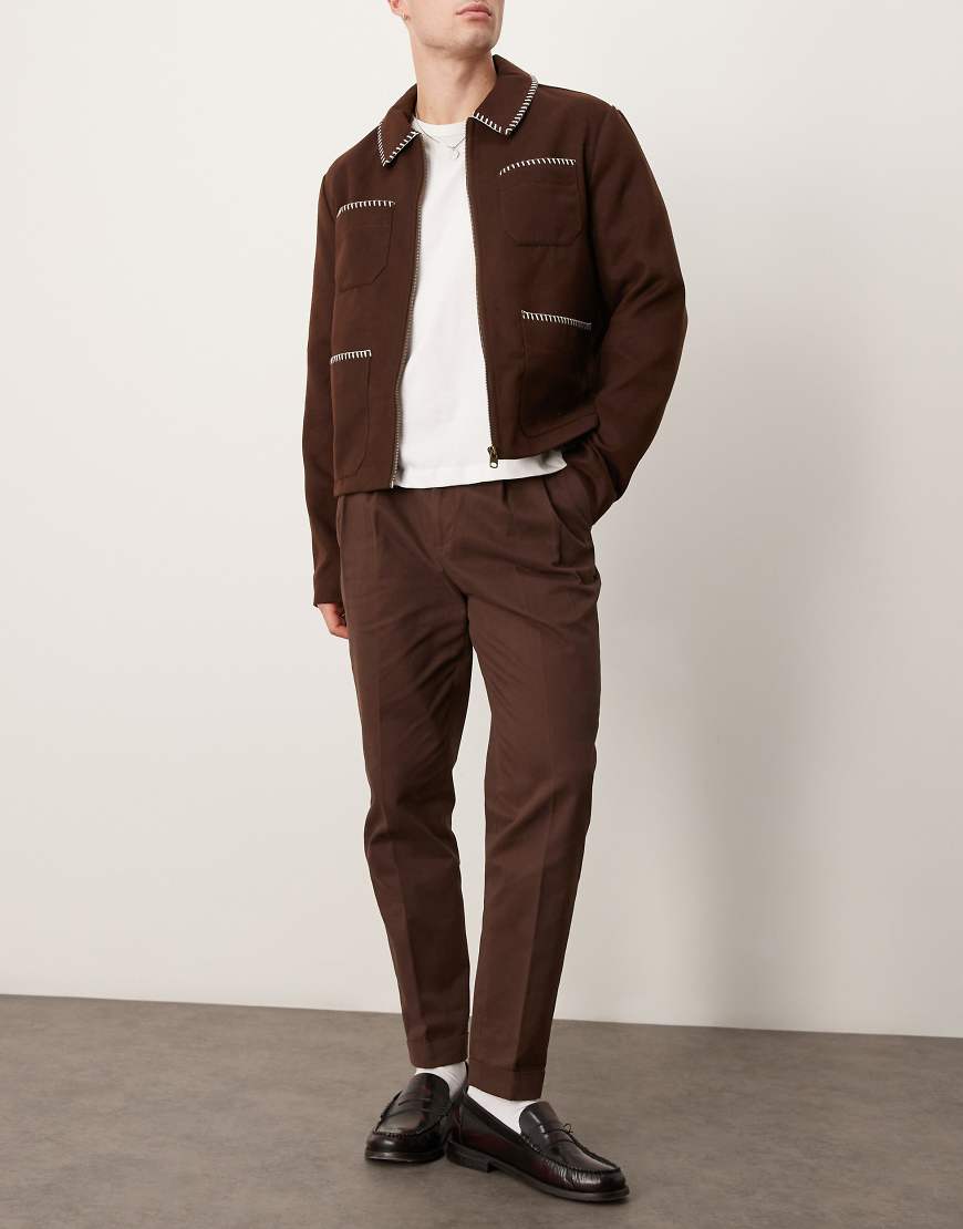 ASOS DESIGN - Elegante, schmal zulaufende Chinohose aus Baumwolle in Braun mit Bundfalten ASOS DESIGN - Elegante, schmal zulaufende Chinohose aus Baumwolle in Braun mit Bundfalten von ASOS DESIGN