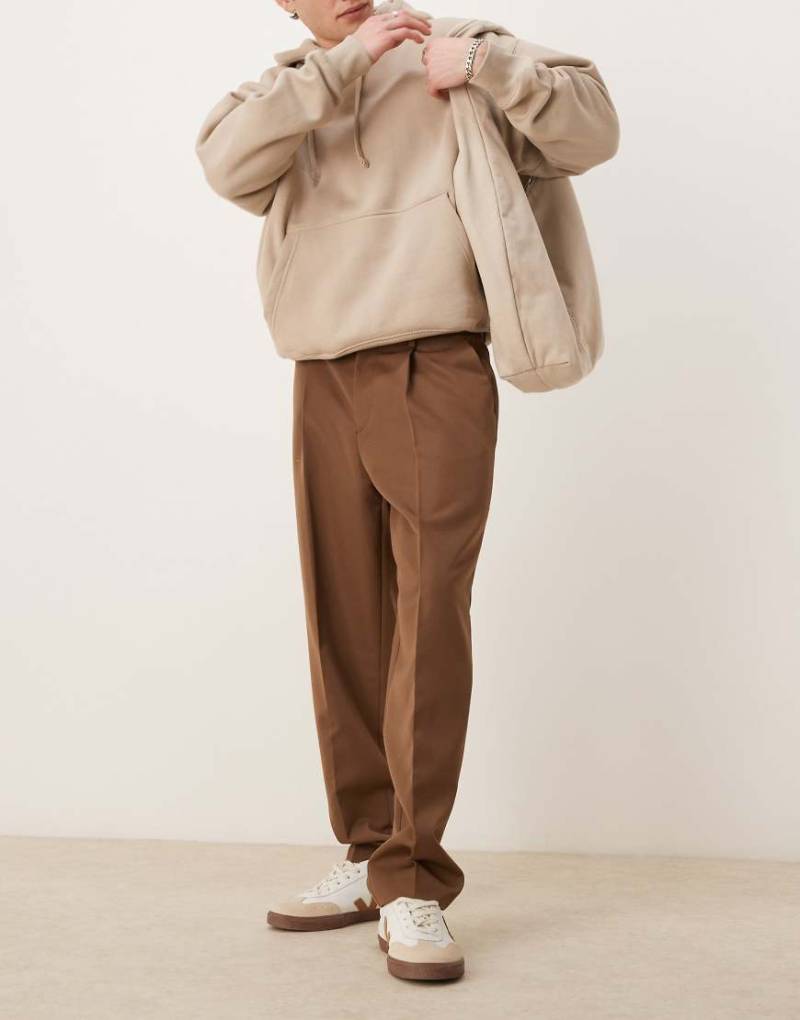 ASOS DESIGN - Elegante, schmal zulaufende Oversize-Hose in Braun mit Bundfalten von ASOS DESIGN
