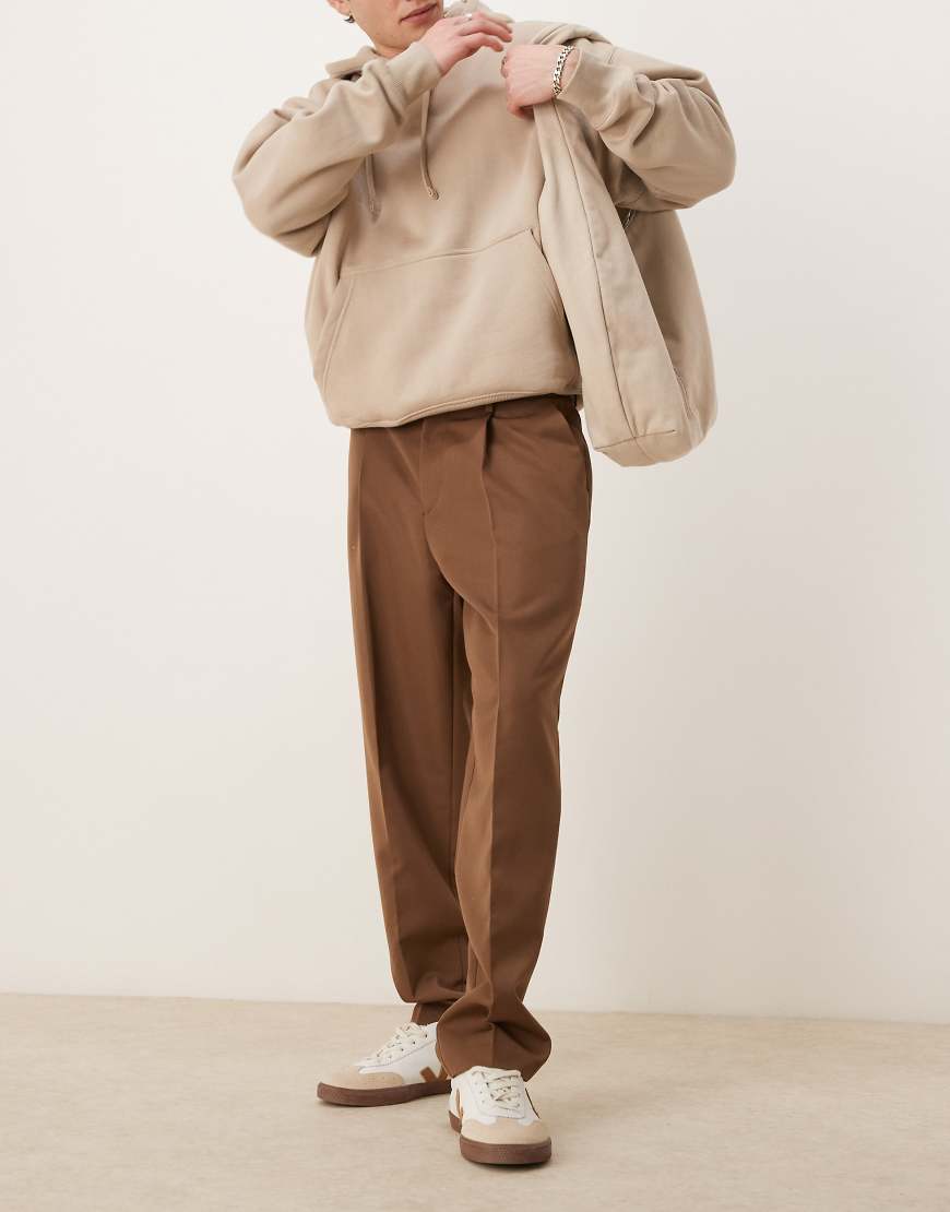 ASOS DESIGN - Elegante, schmal zulaufende Oversize-Hose in Braun mit Bundfalten ASOS DESIGN - Elegante, schmal zulaufende Oversize-Hose in Braun mit Bundfalten von ASOS DESIGN