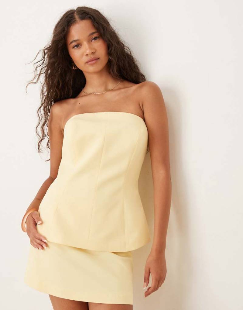 ASOS DESIGN - Elegantes, trägerloses Schößchenoberteil in sanftem Gelb mit tailliertem Schnitt von ASOS DESIGN