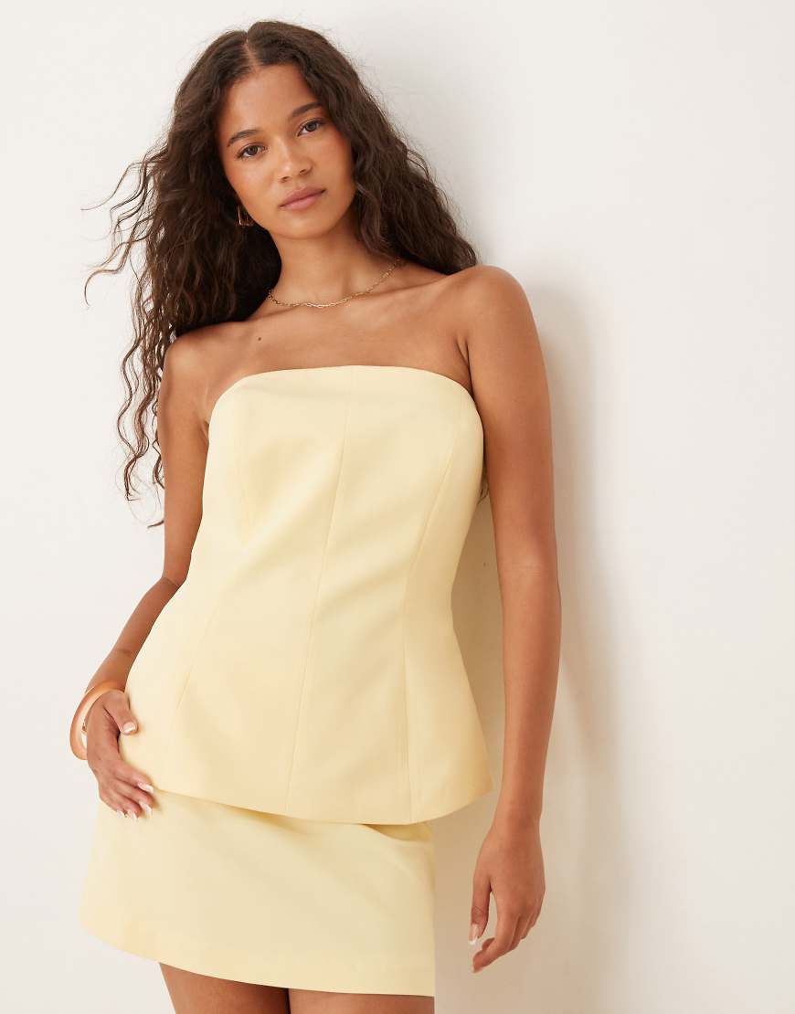 ASOS DESIGN - Elegantes, trägerloses Schößchenoberteil in sanftem Gelb mit tailliertem Schnitt von ASOS DESIGN