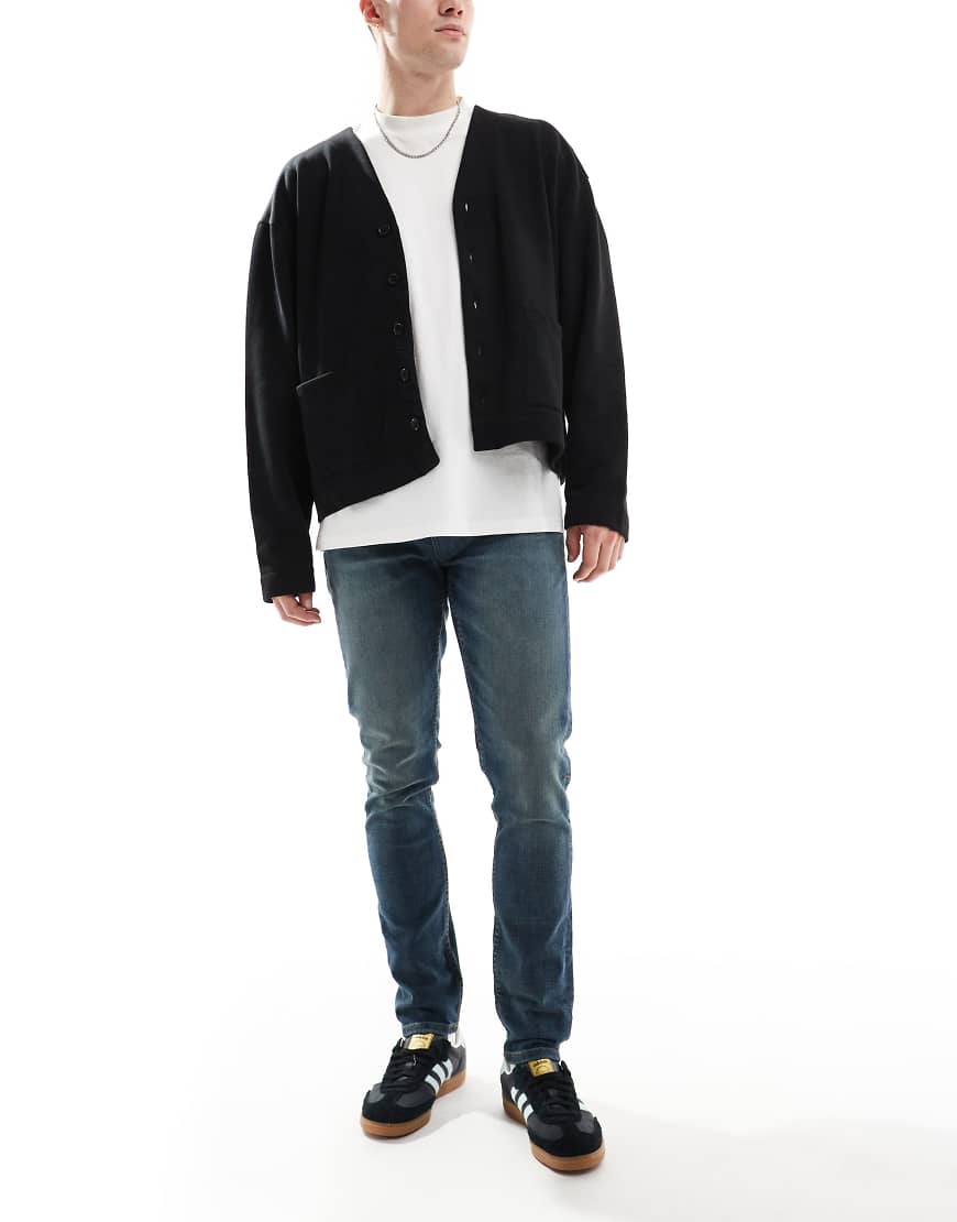 ASOS DESIGN - Eng geschnittene Jeans in gelb getönter, dunkelblauer Waschung ASOS DESIGN - Eng geschnittene Jeans in gelb getönter, dunkelblauer Waschung von ASOS DESIGN