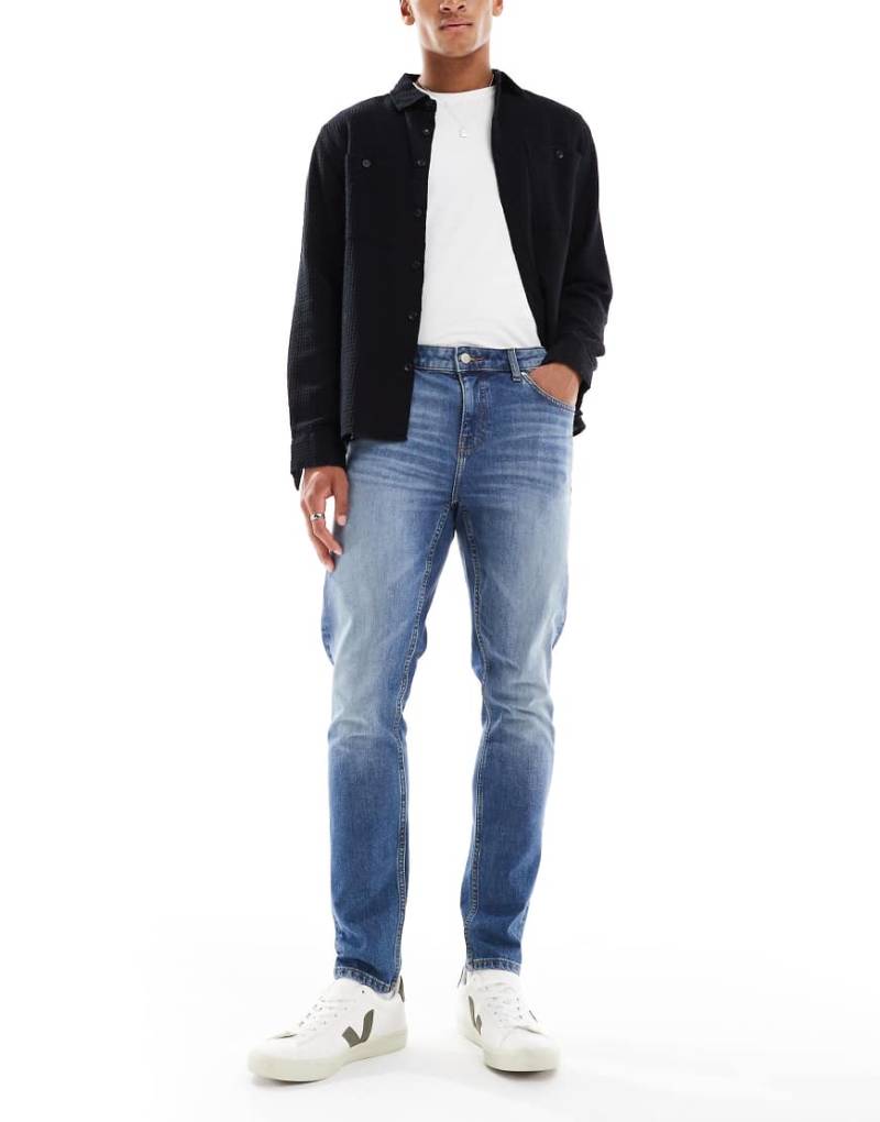 ASOS DESIGN - Enge Jeans in verwaschenem Mittelblau von ASOS DESIGN