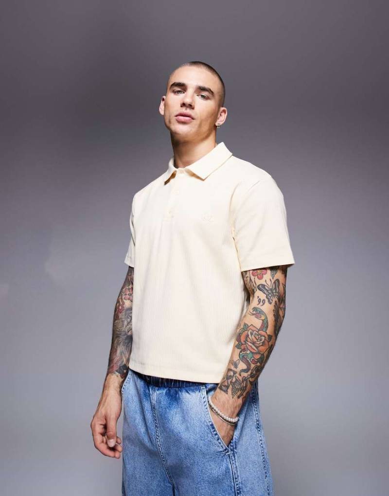 ASOS DESIGN - Geripptes Cropped-Poloshirt in Blassgelb mit Bruststickerei von ASOS DESIGN