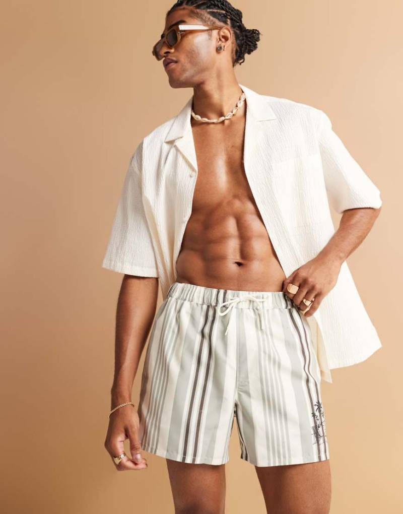 ASOS DESIGN - Gestreifte, kürzere Badeshorts in Creme mit platziertem Print-Weiß von ASOS DESIGN