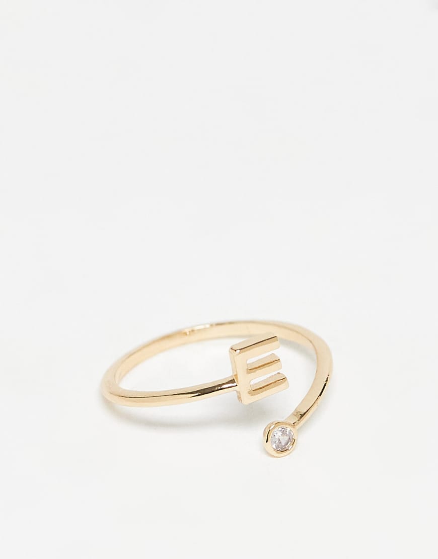 ASOS DESIGN - Goldfarbener Ring mit Wickeldesign, Zirkoniabesatz, „E"-Initiale und Geschenkbeutel von ASOS DESIGN