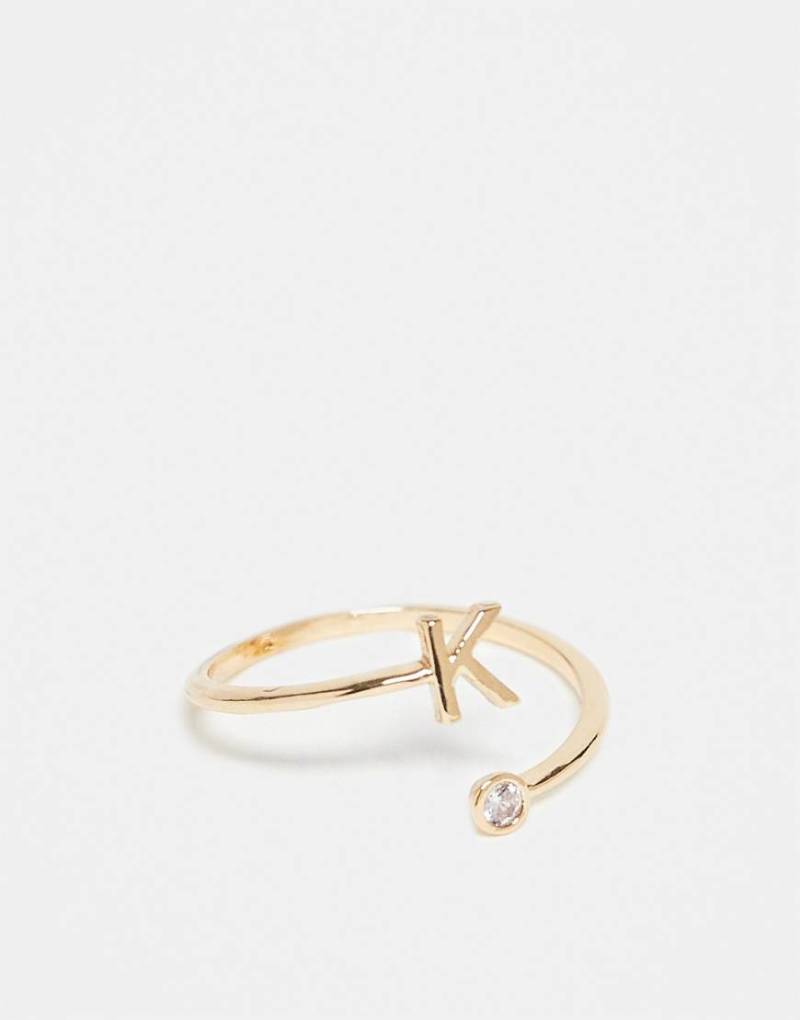 ASOS DESIGN - Goldfarbener Ring mit Wickeldesign, Zirkoniabesatz, „K"-Initiale und Geschenkbeutel von ASOS DESIGN