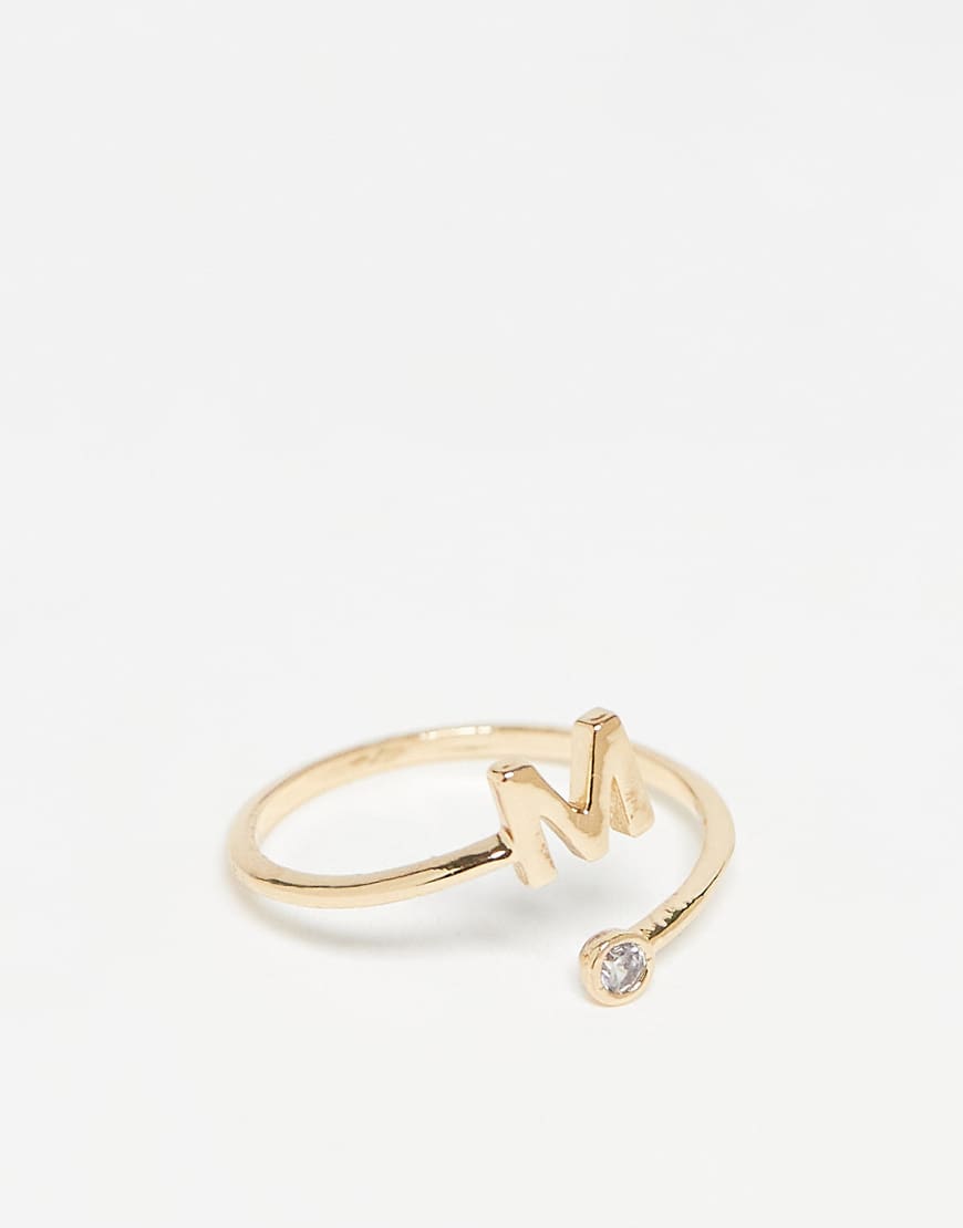 ASOS DESIGN - Goldfarbener Ring mit Wickeldesign, Zirkoniabesatz, „M"-Initiale und Geschenkbeutel von ASOS DESIGN