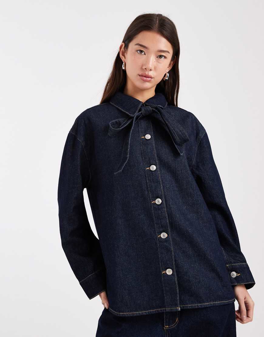 ASOS DESIGN - Jeanshemd mit Schleife am Kragen in Rinse-Waschung-Marineblau von ASOS DESIGN