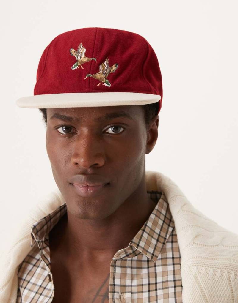 ASOS DESIGN - Kappe in Burgunderrot mit farblich abgesetztem Schirm und Vogel-Motiv von ASOS DESIGN