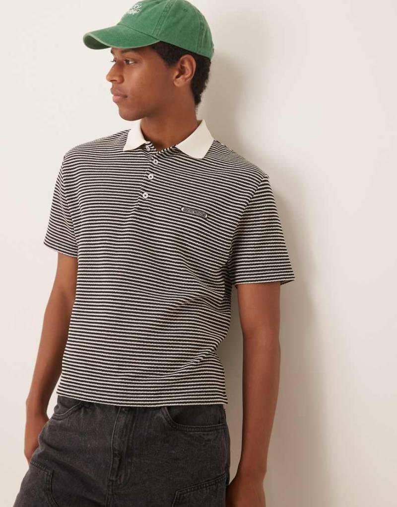 ASOS DESIGN - Kastiges, locker geschnittenes Polohemd in Cremeweiß und Schwarz mit strukturiertem Streifenmuster und Stickerei auf der Brust-Bunt von ASOS DESIGN
