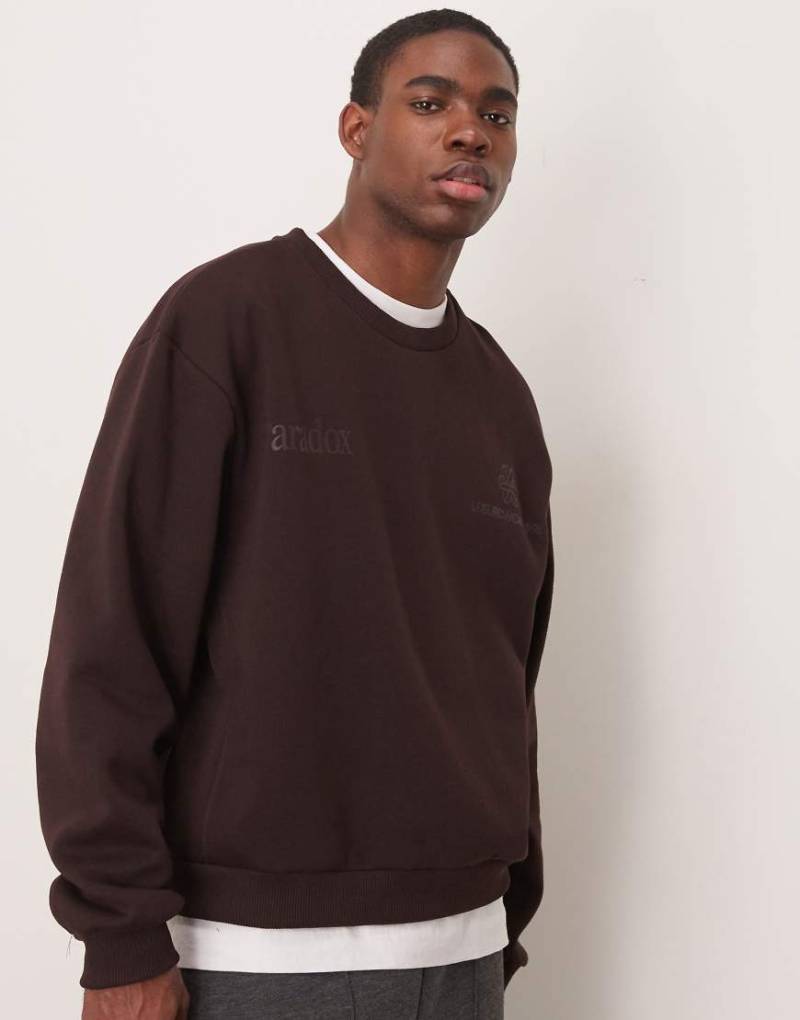 ASOS DESIGN - Kastiges Oversize-Sweatshirt in Dunkelbraun mit Unterarmbahnen und Brust-Print-Rot von ASOS DESIGN