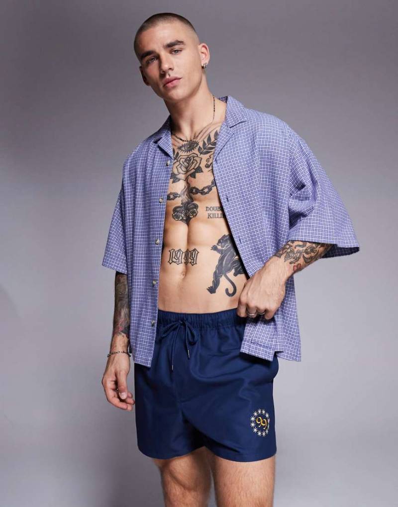 ASOS DESIGN - Kurze Badeshorts in Marineblau mit platziertem Print von ASOS DESIGN