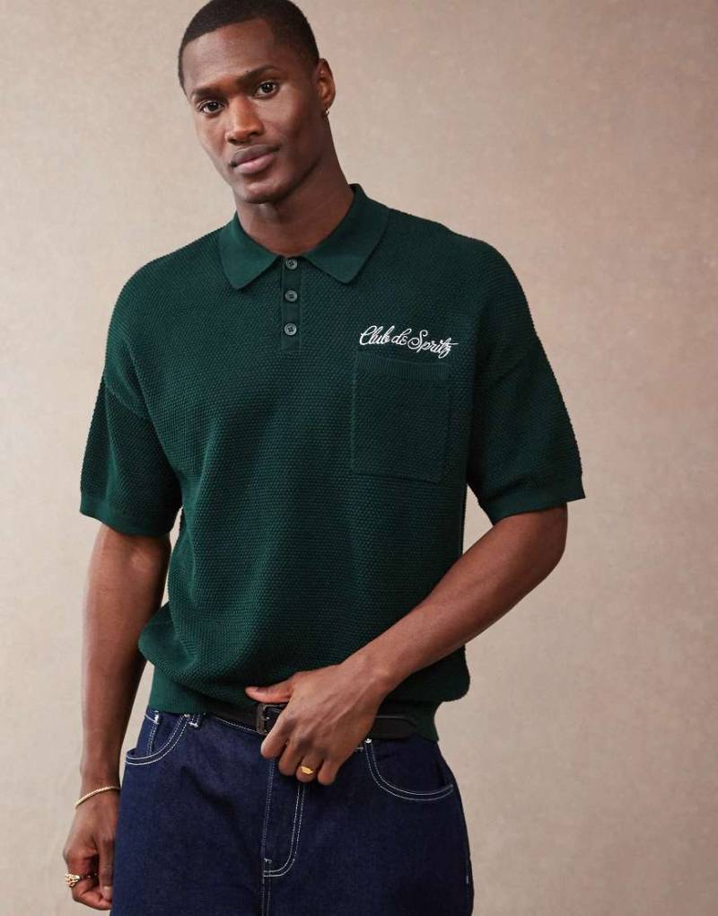 ASOS DESIGN - Lockeres Strick-Polohemd in Dunkelgrün mit Brusttasche und aufgesticktem Text-Braun von ASOS DESIGN