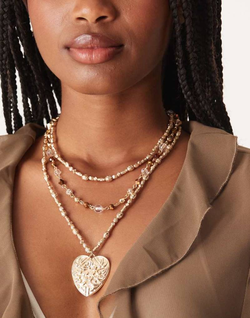 ASOS DESIGN - Mehrreihige Halskette in gehämmerter Goldoptik mit Perlen in Braun und großem Herzanhänger-Goldfarben von ASOS DESIGN