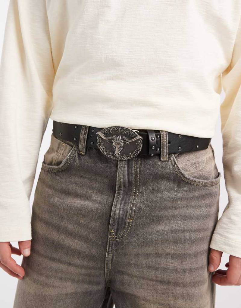 ASOS DESIGN - Mit Nieten besetzter Gürtel in Schwarz aus Kunstleder mit Bullen-Motiv auf der Schnalle von ASOS DESIGN