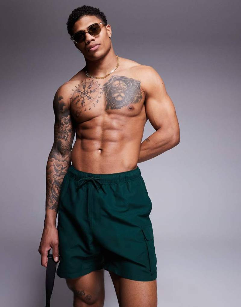 ASOS DESIGN - Mittellange Badeshorts in Grün mit Cargotaschen von ASOS DESIGN