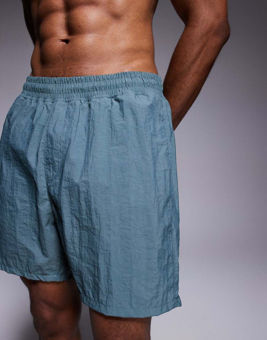 ASOS DESIGN - Halblange Badeshorts in Blau-Grün ASOS DESIGN - Halblange Badeshorts in Blau-Grün von ASOS DESIGN