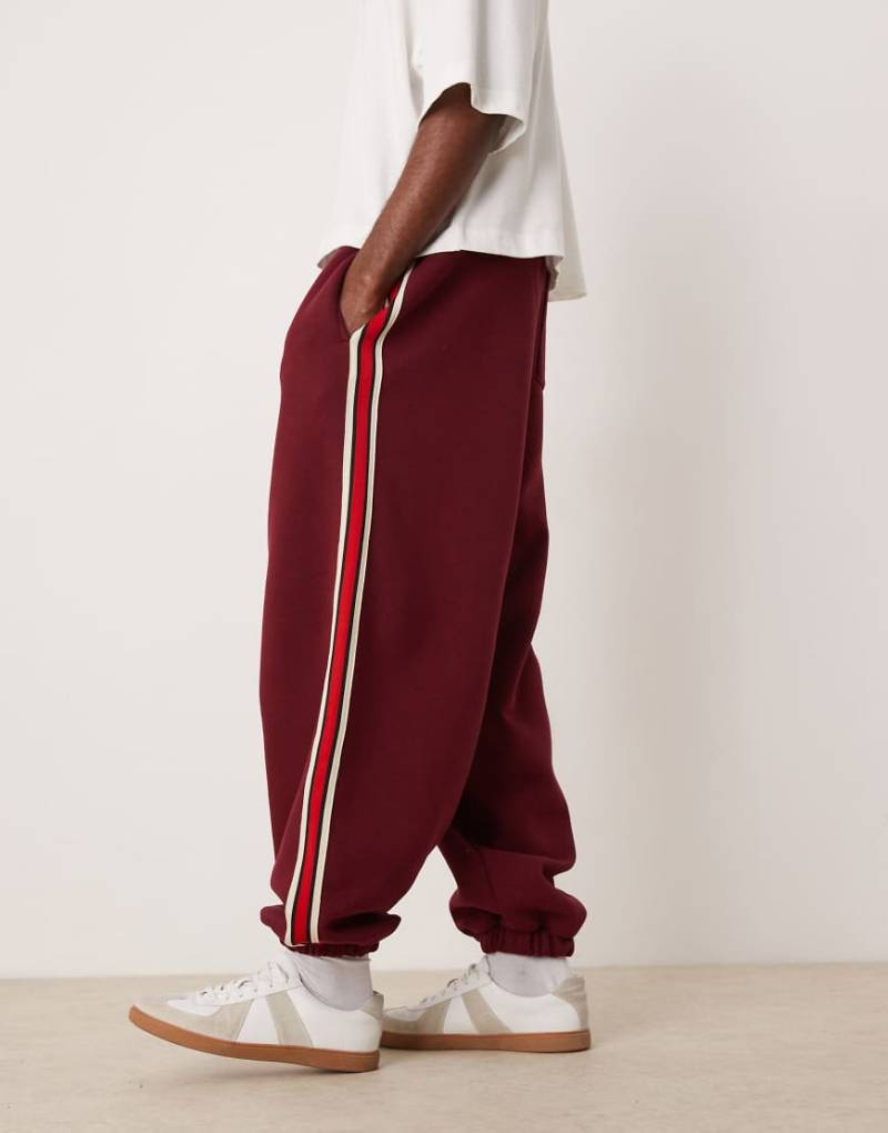 ASOS DESIGN - Jogginghose in Burgunderrot mit weitem Ballon-Schnitt und Zierstreifen von ASOS DESIGN