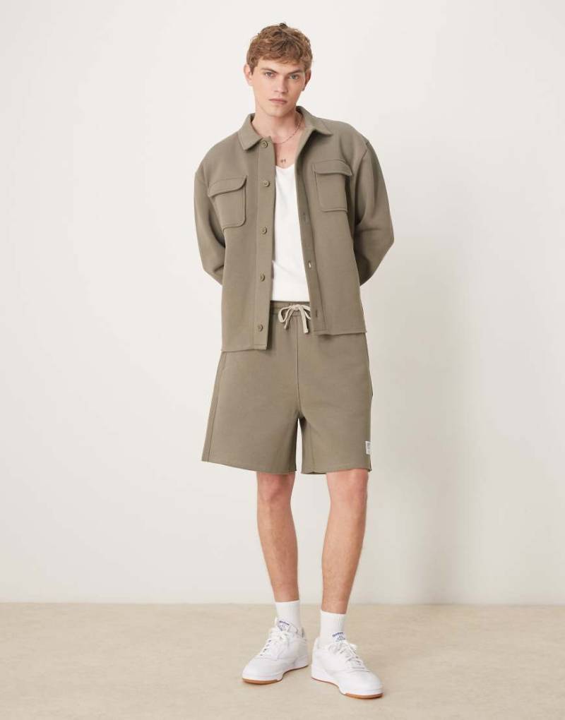 ASOS DESIGN - Oversize-Shorts in Khaki mit gewebtem Aufnäher und offenen Kanten, Kombiteil-Grün von ASOS DESIGN