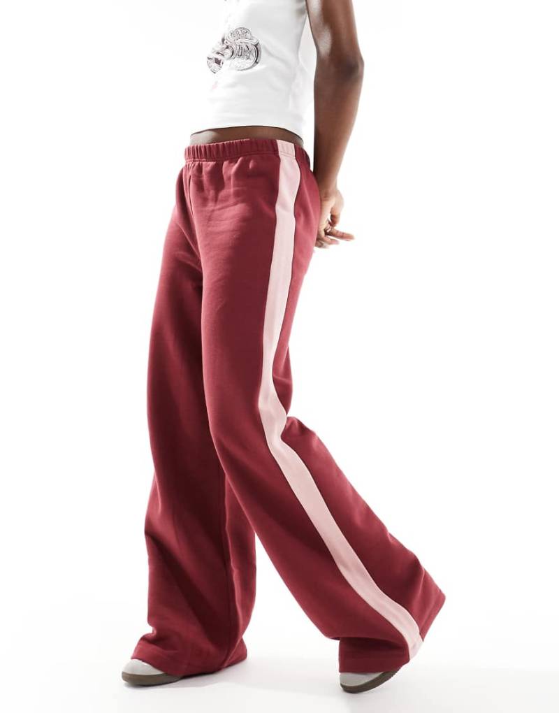 ASOS DESIGN - Oversize-Trainingshose in Burgunderrot mit seitlichem Streifen in Rosa-Bunt von ASOS DESIGN