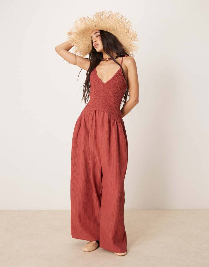 ASOS DESIGN - Polyester-Jumpsuit in Rostrot mit V-Ausschnitt, Knitterstruktur und tiefer Taille von ASOS DESIGN