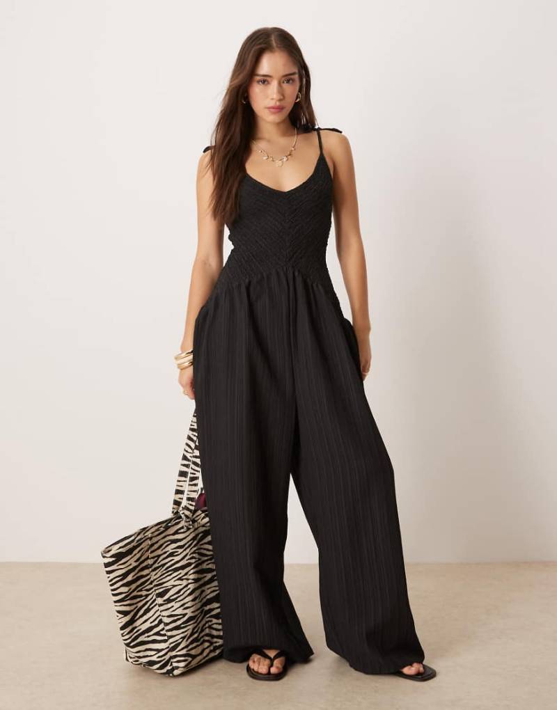 ASOS DESIGN - Polyester-Jumpsuit in Schwarz mit V-Ausschnitt, Knitterstruktur und tiefer Taille von ASOS DESIGN