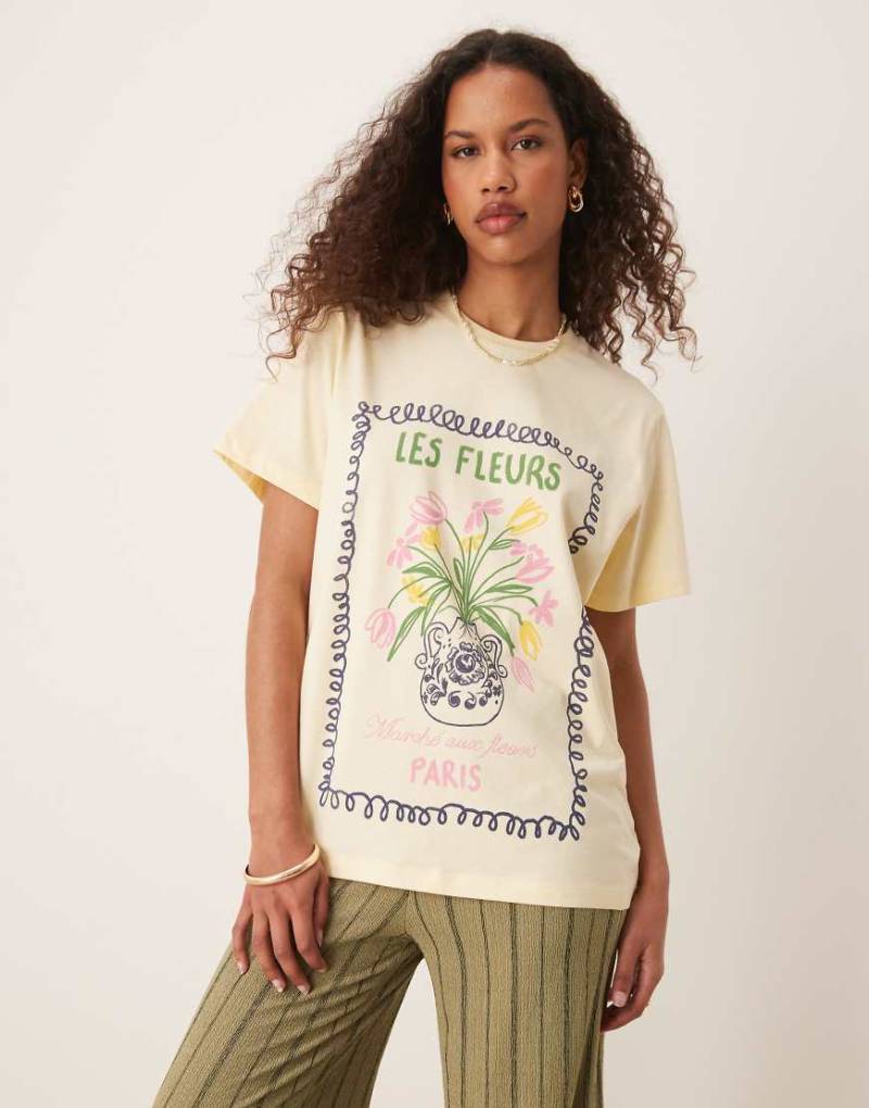ASOS DESIGN - Regulär geschnittenes T-Shirt in verwaschenem Zitronengelb und Fleurs-Grafik von ASOS DESIGN