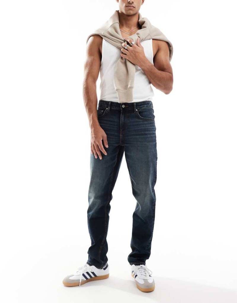 ASOS DESIGN - Schmal geschnittene Jeans in verwaschener, dunkelblauer Tönung von ASOS DESIGN