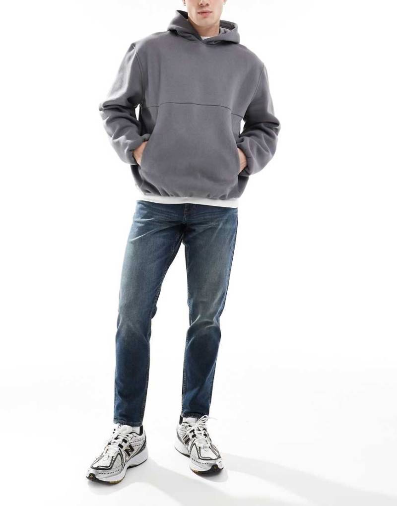 ASOS DESIGN - Schmal zulaufende, elastische Jeans in mittelblauer Waschung von ASOS DESIGN