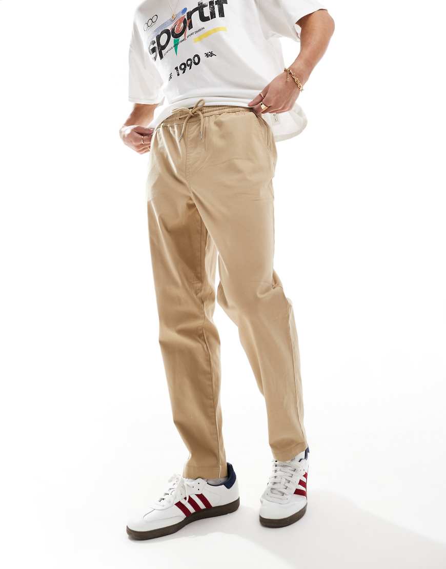 ASOS DESIGN - Schmal zulaufende Chino-Schlupfhose in Beige mit elastischem Bund-Neutral ASOS DESIGN - Schmal zulaufende Chino-Schlupfhose in Beige mit elastischem Bund-Neutral von ASOS DESIGN