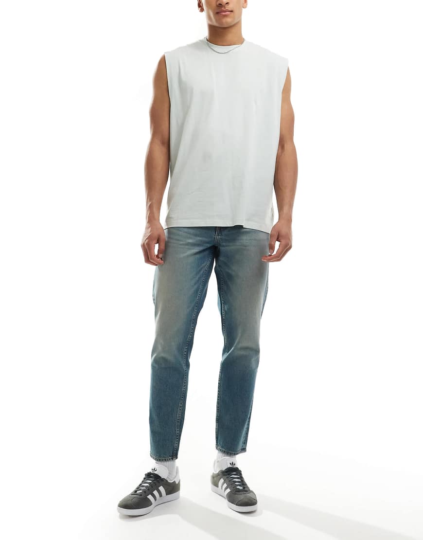 ASOS DESIGN - Schmal zulaufende Jeans in hellblauer Waschung mit Farbstich von ASOS DESIGN