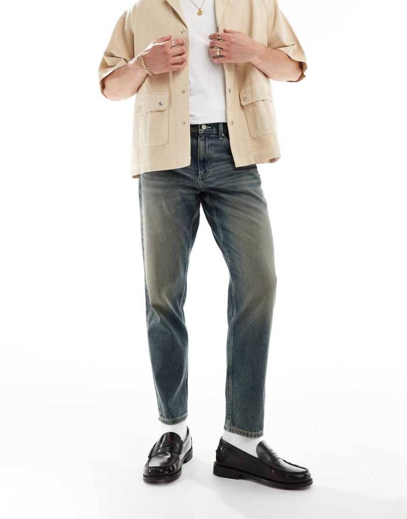 ASOS DESIGN - Schmal zulaufende Jeans in mittelblauer Waschung von ASOS DESIGN