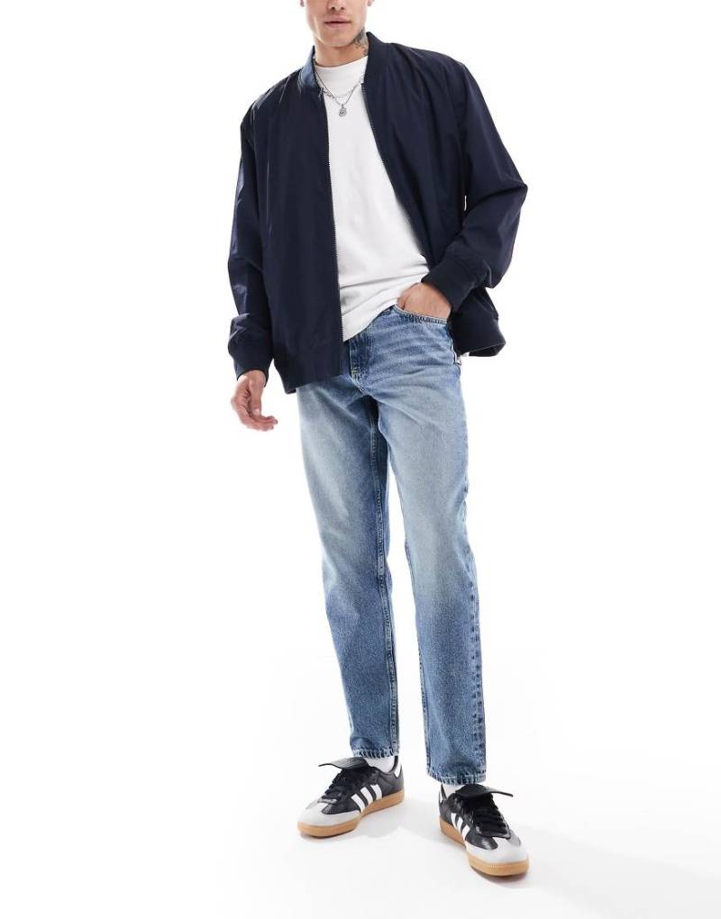 ASOS DESIGN - Schmal zulaufende Jeans in mittelblauer Waschung von ASOS DESIGN