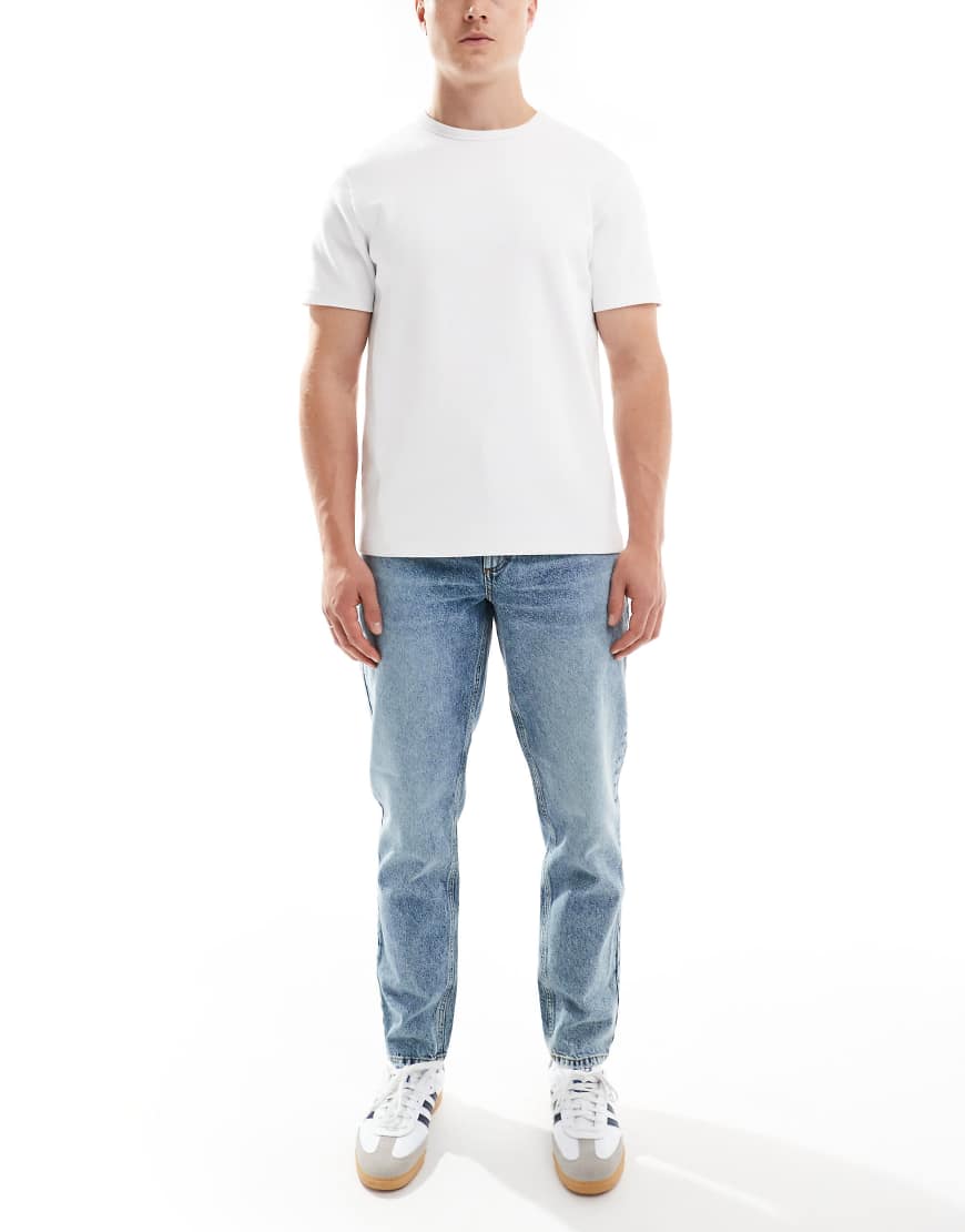 ASOS DESIGN - Schmal zulaufende Jeans in mittelblauer Waschung ASOS DESIGN - Schmal zulaufende Jeans in mittelblauer Waschung von ASOS DESIGN