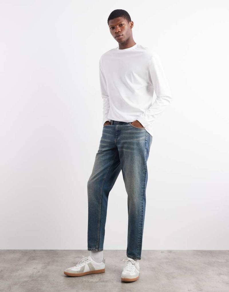 ASOS DESIGN - Schmal zulaufende Jeans in verwaschenem Mittelblau von ASOS DESIGN