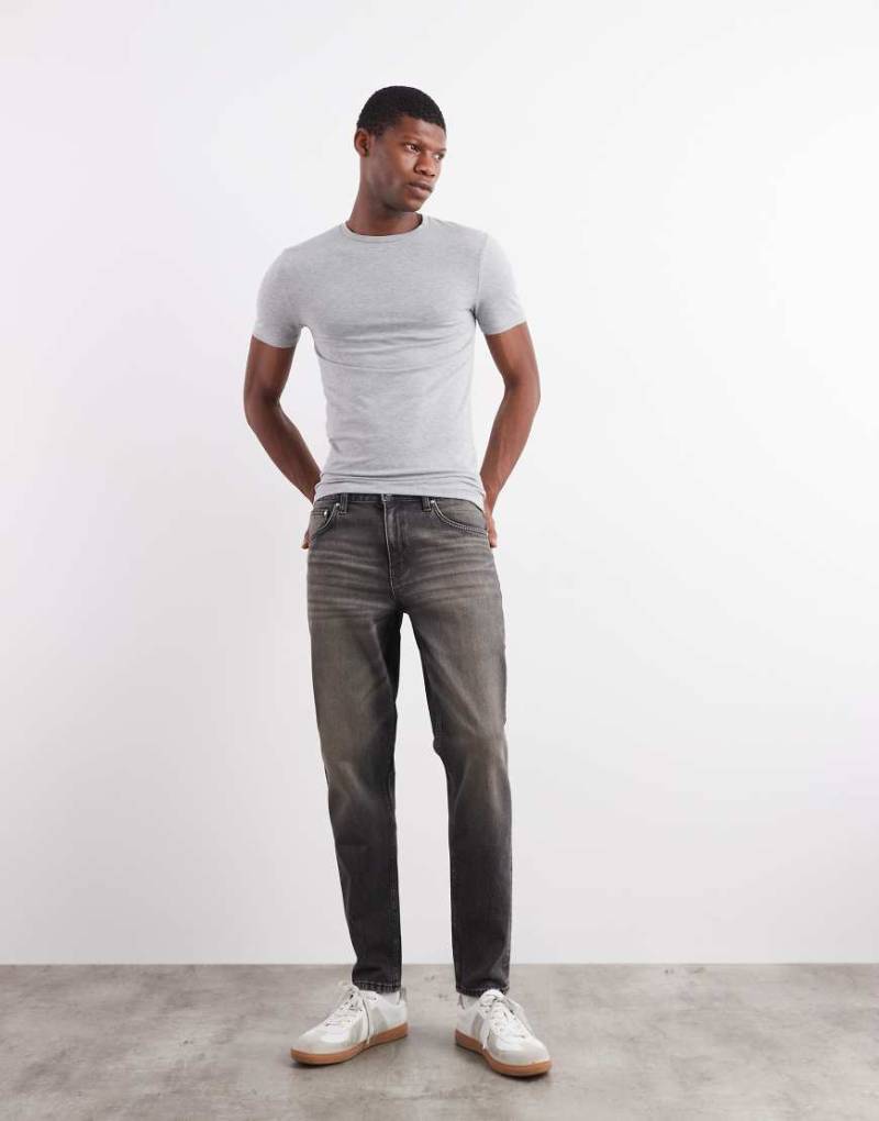 ASOS DESIGN - Schmal zulaufende Jeans in verwaschenem Schwarz mit Gelbstich von ASOS DESIGN