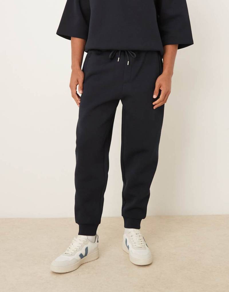 ASOS DESIGN - Schmal zulaufende Jogginghose aus schwerem neoprenartigem Stoff in Marineblau von ASOS DESIGN