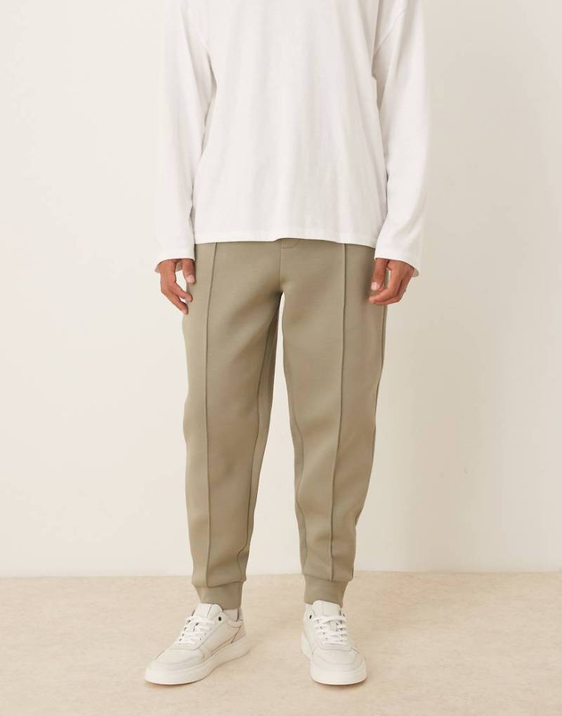 ASOS DESIGN - Schmal zulaufende Jogginghose aus schwerem, neoprenartigem Stoff in Khaki mit Biesen-Grün von ASOS DESIGN