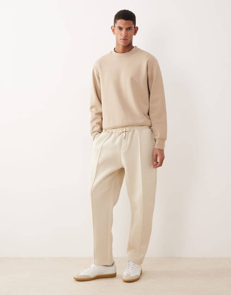 ASOS DESIGN - Schmal zulaufende Jogginghose aus schwerem neoprenartigem Stoff in Beige-Neutral von ASOS DESIGN