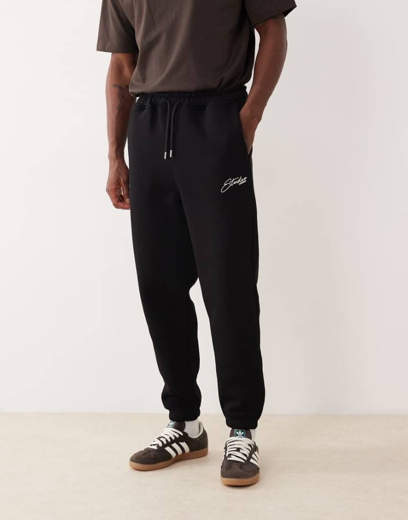 ASOS DESIGN - Schmal zulaufende Jogginghose in Schwarz mit aufgesticktem Motiv von ASOS DESIGN