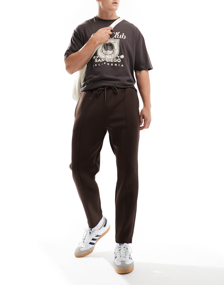 ASOS DESIGN - Schmal zulaufende Jogginghose in brauner Neopren-Optik ASOS DESIGN - Schmal zulaufende Jogginghose in brauner Neopren-Optik von ASOS DESIGN