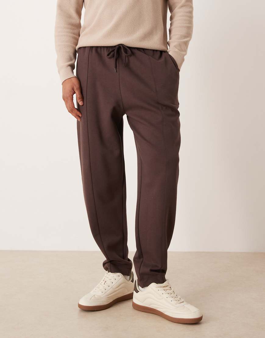 ASOS DESIGN - Schmal zulaufende Jogginghose mit Zierfalten in Braun-Brown von ASOS DESIGN