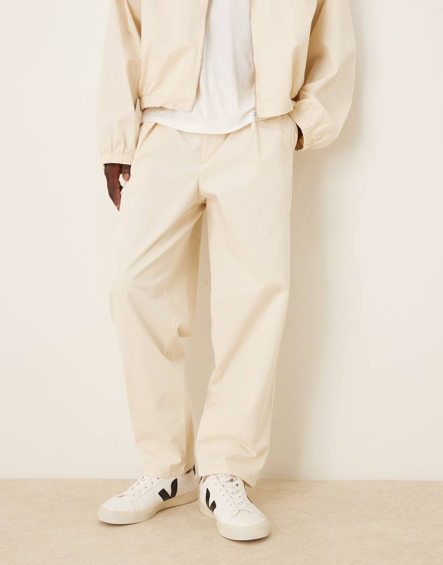 ASOS DESIGN - Schmal zulaufende Oversize-Hose in Ecru mit tiefem Faltendetail, Kombiteil-Neutral von ASOS DESIGN