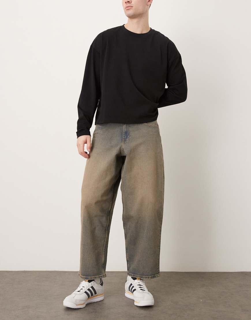 ASOS DESIGN - Schmal zulaufende Oversize-Jeans in mittelblauer Waschung mit braunem Farbstich-Brown von ASOS DESIGN